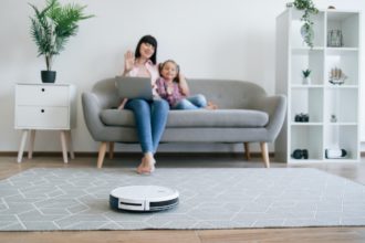 Cleaning robot doing job while owners having online talk