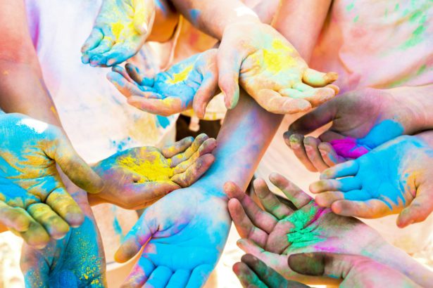 Colorful hands of friends group having fun at beach party on holi color festival
