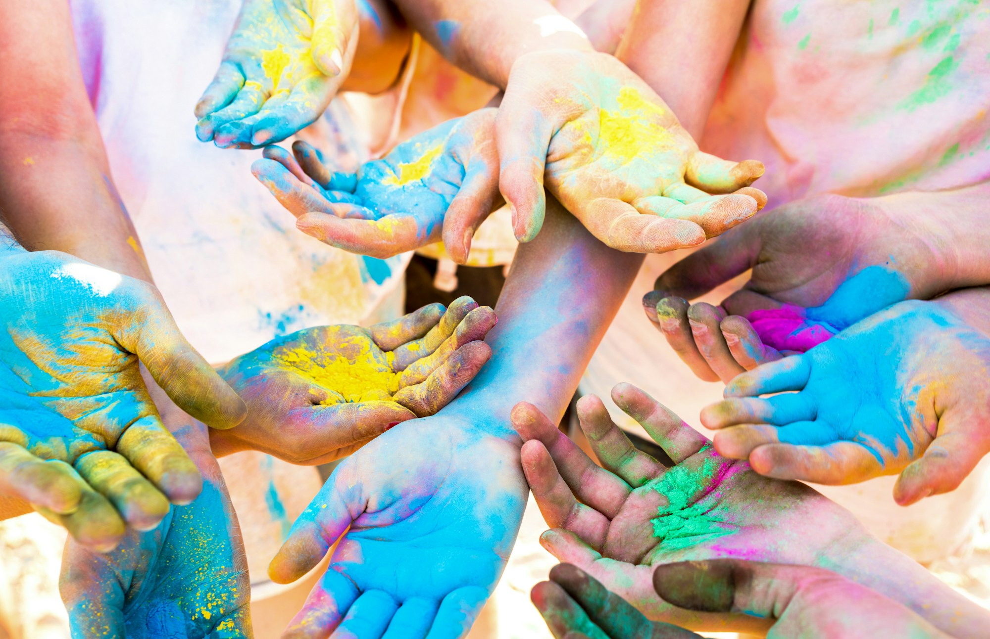 Colorful hands of friends group having fun at beach party on holi color festival