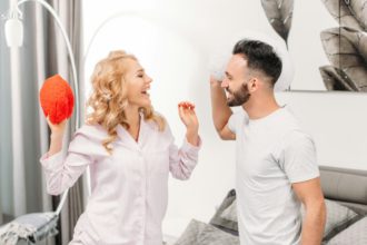 Laughing couple looking at each other and holding toy hearts