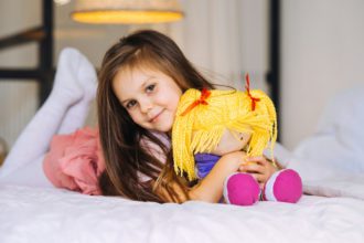 little girl with a toy on the bed