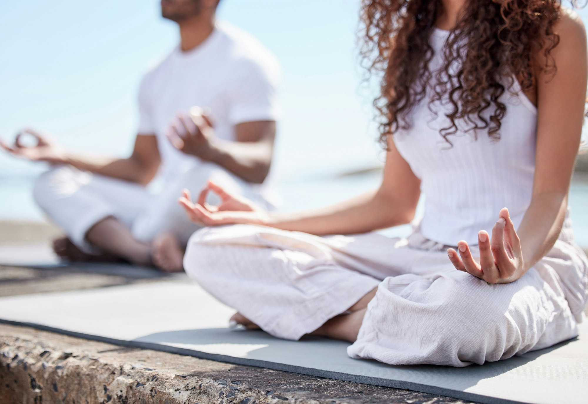 Mindful of mental health. Cropped shot of an unrecognizable couple practicing yoga at the beach.