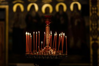 On a large Church copper candlestick lit a small candle. Orthodox Christian Church. Religion