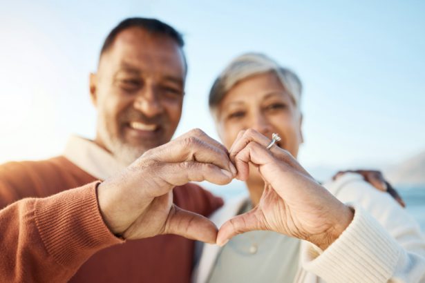 Senior couple, heart hands and beach portrait for love, icon or smile in summer, sign language or s