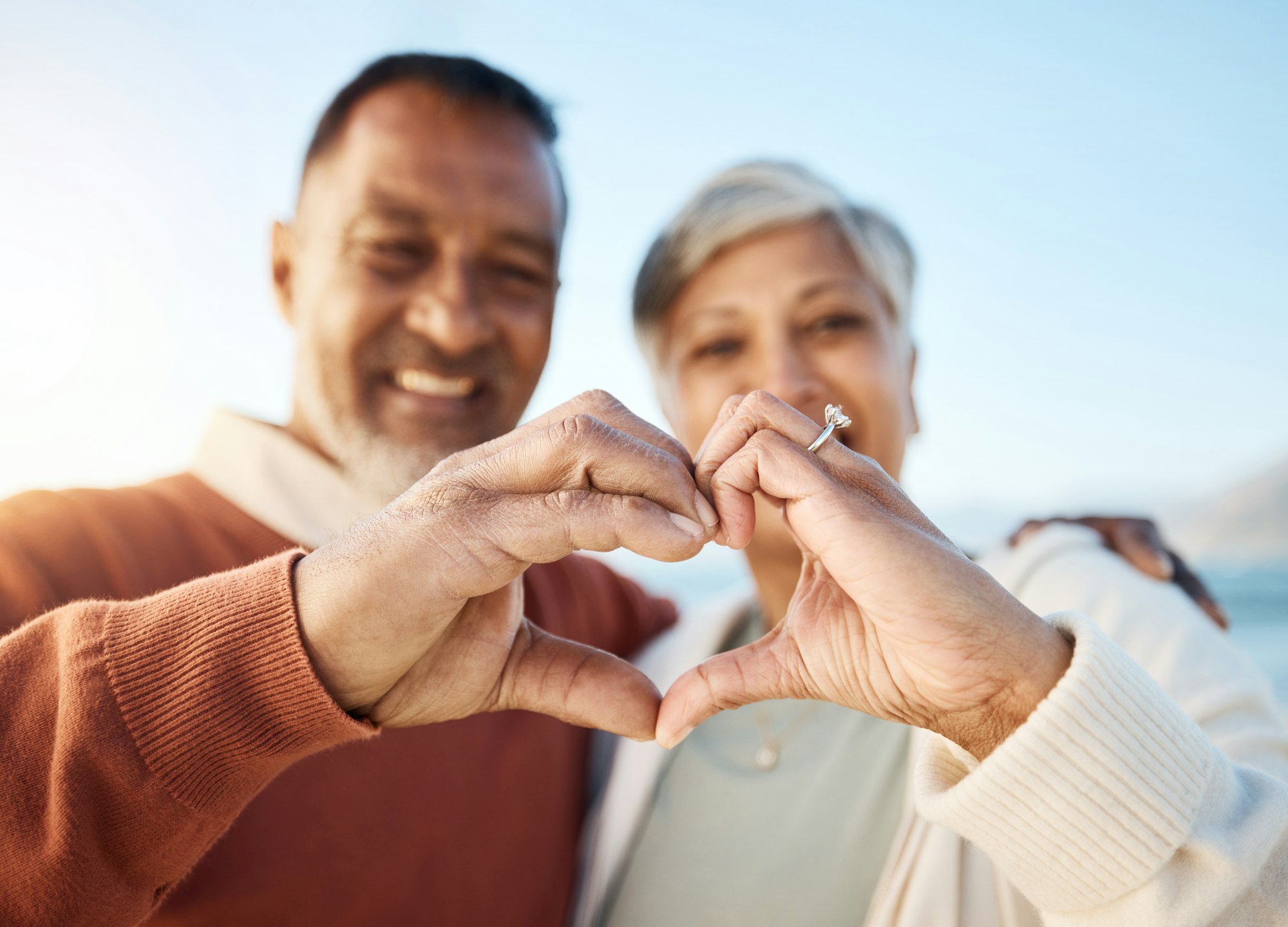 Senior couple, heart hands and beach portrait for love, icon or smile in summer, sign language or s