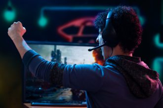 Young adult man shouting in excitement after winning a video game on his gamer setup