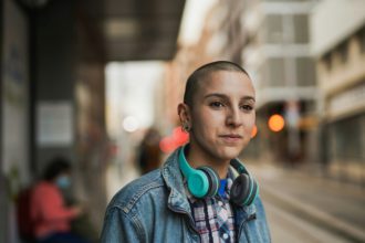 Young bald woman waiting on the tram station in the city