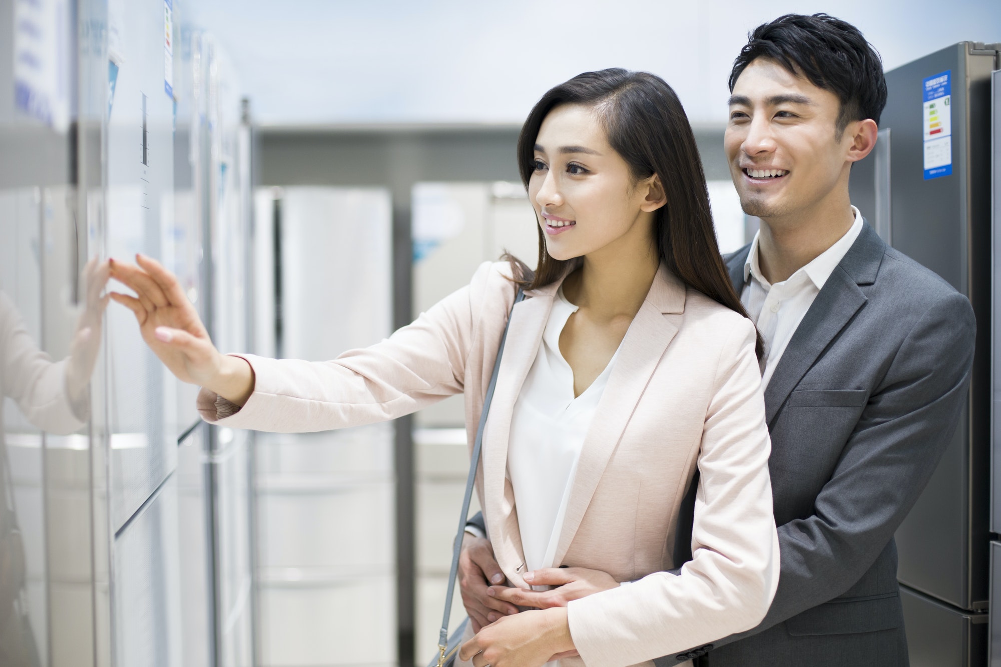 Young couple buying refrigerator in electronics store