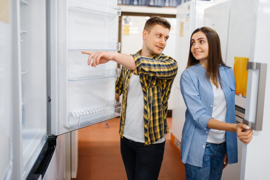 Young couple choosing refrigerator in store